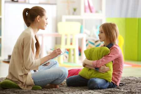 Young female psychologist working with teenager girl in office